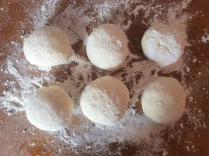 6 dough balls on a surface with flour