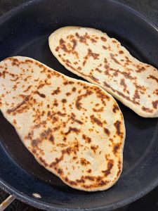 Fresh flatbread naan cooks in a nonstick frying pan