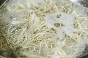 Wok noodles boiling in pot