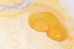Electric mixer with dough with two eggs in background.