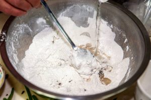 mixing dough in a metal bowl for cypriot pita bread