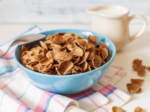 Healthy breakfast with wheat buckwheat bran cereal with milk in blue ceramic bowl. Ready to eat